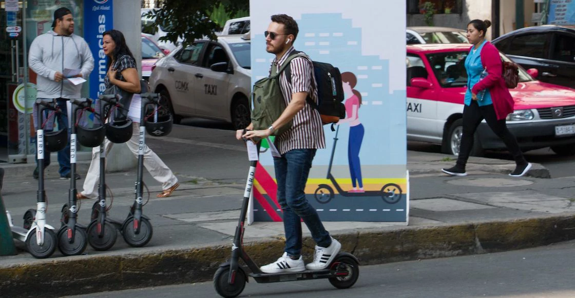 Usuario de scooter eléctrico en la CDMX, con más unidades de renta estacionadas en la acera, dentro del nuevo marco de regulación de movilidad.